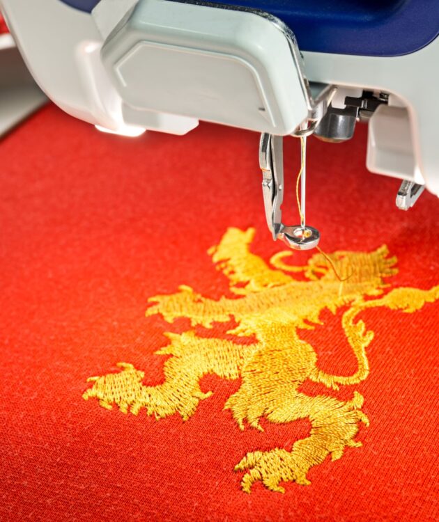 Embroidery machine and  gold lion design on red cotton fabric shirt, close up picture